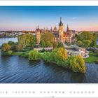Text: "Schweriner Schloss, Schwerin, Mecklenburg-Vorpommern." Eine prächtige Schlossanlage auf einer Insel, umgeben von Wasser und Bäumen.