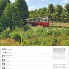 Juni, 25. Woche, 21. Sommeranfang. Bild: Rote Straßenbahn neben üppigem Grün, blauer Himmel mit Wolken.