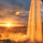 Text über Island: Wasserschleier des Seljalandsfoss im Sonnenlicht. Kalender für Juni und Juli. Sonnenuntergang und Wasserfall.