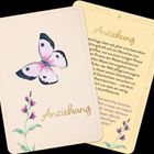 "Anziehung" in goldener Schrift, Illustration eines rosa Schmetterlings und rosa Blumen auf hellem Hintergrund.