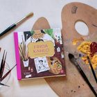 "FRIDA KAHLO Ein Leben in allen Farben" Buch auf einer Palette mit Pinseln und Farbe.