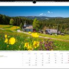 Juni-Kalenderblatt. Blühende Wiese mit gelben Blumen, Kirche, und Hütten vor Wald und Hügeln unter klarem Himmel.