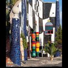 VI 2027. Eine farbenfrohe, wellenförmige Architektur mit Mosaikfliesen und bunten Säulen.