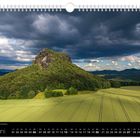 Juni; Beeindruckendes Lichtspiel am Lilienstein; Landschaft mit bewaldetem Hügel, Feldern und dramatischem Wolkenhimmel.