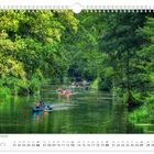 "Sommerlicher Hochbetrieb auf der Spree". Juni-Kalender. Kanus in grünem Fluss, umgeben von üppigen Bäumen.