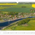 Juni-Kalenderblatt. Luftbild eines Dorfes mit Kirche, grünen Feldern und blühendem Rapsfeld. Fähre an einem Hafen.