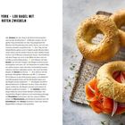 "New York – Lox Bagel mit roten Zwiebeln" Rezept mit Zutaten und Anweisungen. Rechts im Bild sind frische Bagels zu sehen.