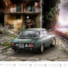 JUNI Kalender mit Alfa Romeo 1600 GTA, ein grünes Auto auf gepflastertem Weg vor einem historischen Gebäude am See.
