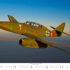 Kalendermonat Juni. Ein Militärflugzeug fliegt über eine Landschaft unter klarem Himmel.
