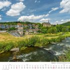 "Wuppertal - Fischtreppe am Beyenburger Stausee." Kalenderblatt Juni 2027. Fluss, Wiese, bunte Häuser und Kirche im Hintergrund.