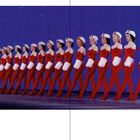 1950, "Title goes here". Eine Reihe Frauen in roten Kostümen und weißen Handschuhen stehen synchron auf einer Bühne.