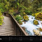 Text: "Neuseeland 06". Kalenderansicht. Eine Holzbrücke führt durch üppigen Wald neben einem rauschenden, felsigen Bach.