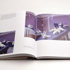 Ein Buch ist geöffnet. "Porcelain, Poetry, 2014" zeigt weiße Skulpturen auf blauen Tischen in einem violetten Raum.