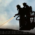 Kalender unten mit Daten und Wochentagen. Zwei Feuerwehrleute spritzen Wasser von einer Hebebühne.