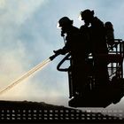 Der untere Rand zeigt eine Kalenderübersicht für Juni. Zwei Feuerwehrleute spritzen Wasser von einer Plattform.