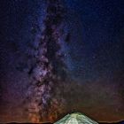 Keine Texte erkennbar. Eine Jurte steht unter einem sternenklaren Nachthimmel mit der Milchstraße darüber.