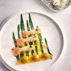 Kein Text. Auf einem Teller liegen grüne Bohnen mit Garnelenstücken und gelber Sauce, daneben eine Schale mit Reis.