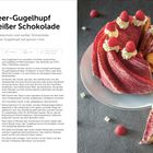 Himbeer-Gugelhupf mit weißer Schokolade, serviert auf einem Teller, dekoriert mit Sahne und Himbeeren. Rezept auf der linken Seite.