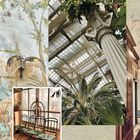 Palmenhaus mit Stahlträgern und Palmen, dekorierte Wände mit Pflanzenmotiven, eine Wandlampe und vier grüne Stühle.