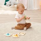 Ein Kleinkind sitzt auf einem Teppich und spielt mit Holzpuzzles in einem gemütlich eingerichteten Raum.