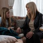 Eine blonde Frau und ein Mädchen sitzen auf einem Sofa und unterhalten sich eindringlich in einem gemütlichen Raum.