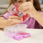 Text: "Jelly Bear". Ein Kind in lila Hemd gießt rosa Flüssigkeit aus einer Tüte in einen kleinen Plastikbecher.