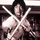 Ich kann die Person nicht identifizieren. Ein Mann hält zwei gekreuzte Stöcke in einer kämpferischen Pose.