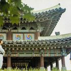 Mehrere Menschen stehen vor einem traditionellen, verzierten asiatischen Gebäude.