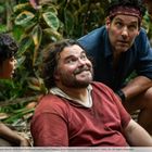 Vier Personen in einem dichten Dschungel, teils sitzend, teils kauernd, schauen einander an. Sie wirken konzentriert.