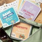 "NAME THAT SONG! Sing, wenn du’s fühlst!", "WAS SCHÄTZT DU?", "WORTKETTE". Kartenspiele, eine Tasche und Sonnenbrille.