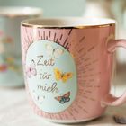 "Zeit für mich" steht auf einer rosa Tasse mit Schmetterlingen und goldenen Strahlen.