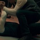 Zwei Männer ringen miteinander auf dem Boden. Im Hintergrund liegen Menschen regungslos am Boden.