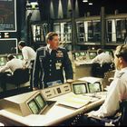 Militärische Kommandozentrale mit Offizieren in Uniform, an Konsolen arbeitend, großer Bildschirm zeigt Karten- und Datenanzeige.