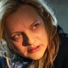 Keine Texte erkennbar. Eine Frau mit blonden Haaren schaut ernst zur Seite, in einer Nahaufnahme.