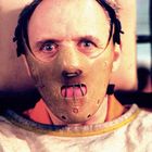 Ein Mann mit intensiven Augen trägt eine Maulkorb-Maske. Sein Blick ist ernst und konzentriert.