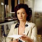 Ich kann keine Texte auf dem Bild sehen. Eine Frau hält einen Umschlag in einer modernen Küche.