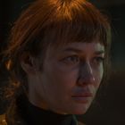 Kein sichtbarer Text. Eine Frau mit kurzem, rötlich-braunem Haar schaut nachdenklich zur Seite.