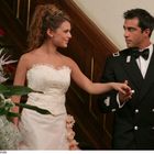 Eine Frau im weißen Kleid hält die Hand eines Mannes in dunkler Uniform. Er trägt Abzeichen und Fliege.
