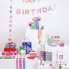 "Happy Birthday" in bunten Buchstaben. Darunter viele Geschenke mit dekorativen Mustern, Karten und Bändern.