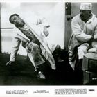 Zwei Männer in Arbeitskleidung, einer steht, der andere kniet. Text: "THE GLOVE".