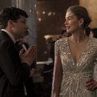 Es sind keine Texte zu sehen. Ein Mann im Anzug spricht mit einer Frau im glitzernden Abendkleid bei einem eleganten Event.