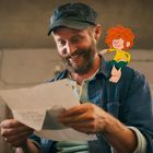 Eine Person lacht beim Lesen eines Briefs. Eine animierte Figur sitzt lächelnd auf der Schulter.