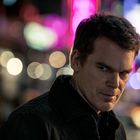 Kein Text vorhanden. Ein Mann steht nachts in einer Stadt, unscharfe Lichter im Hintergrund.