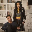 Ein Mann hält ein Tablet vor einem Bücherregal. Neben ihm steht eine Frau im gelben T-Shirt mit Schriftzug.