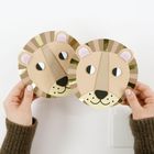 Zwei gebastelte Masken in Form von Löwengesichtern aus Papier, gehalten von Händen. Sie haben goldene und braune Streifen.