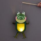 Ein Frosch aus Papier mit einem leuchtenden Bauch, gehalten an einem Stock.