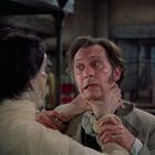 Ein Mann wird von einem anderen bei hellem Licht gewürgt; die Szene wirkt dramatisch und angespannt.
