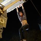 Die Zahl „4“ ist auf einem metallischen Fahrgeschäft zu sehen. Eine Frau hängt daran, mit blutigem Gesicht und gestreiftem Oberteil.