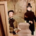 Keine erkennbaren Texte. Zwei Männer in historischer Kleidung; einer malt, der andere steht mit Stock und Zylinder.