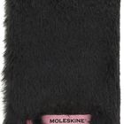 Der Text "MOLESKINE" ist auf einem rosa Band sichtbar. Ein schwarzes, flauschiges Notizbuch ist mit rosa Elementen verziert.